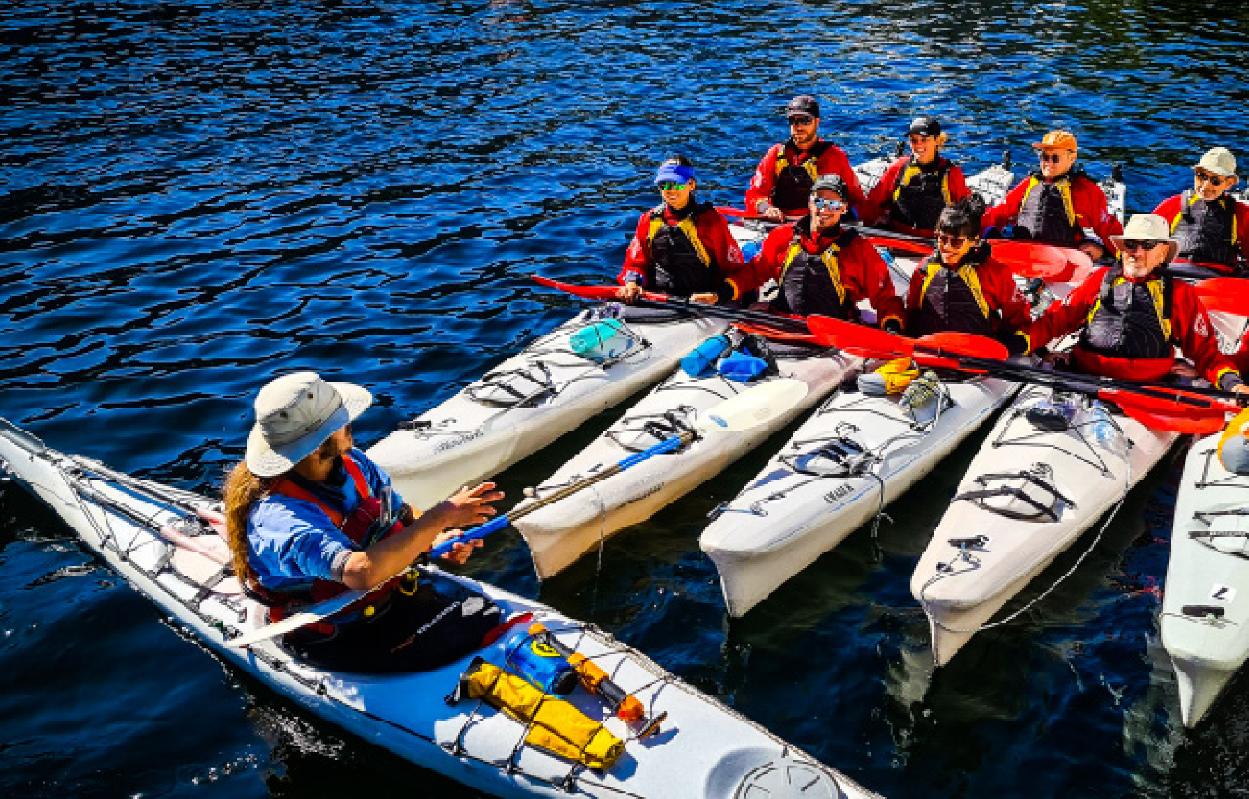 Five kayaks rafted together and guide speaking to kayakers